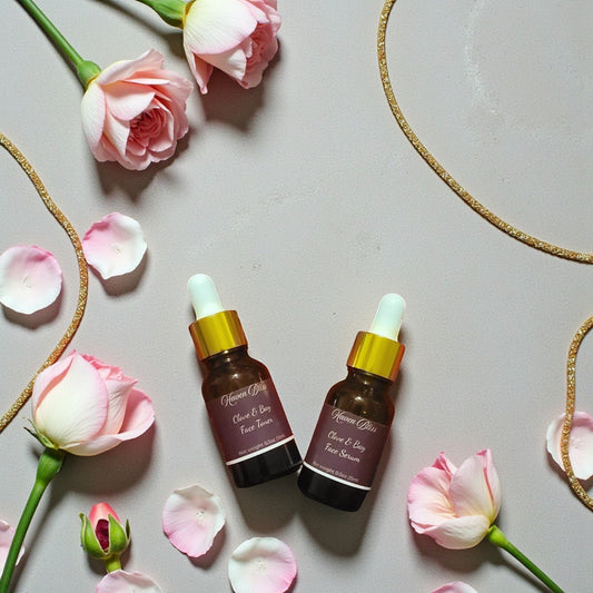 Haven Bliss Skincare Clove & Bay Ritual Duo, two amber glass dropper bottles with gold accents, surrounded by pink roses and petals.